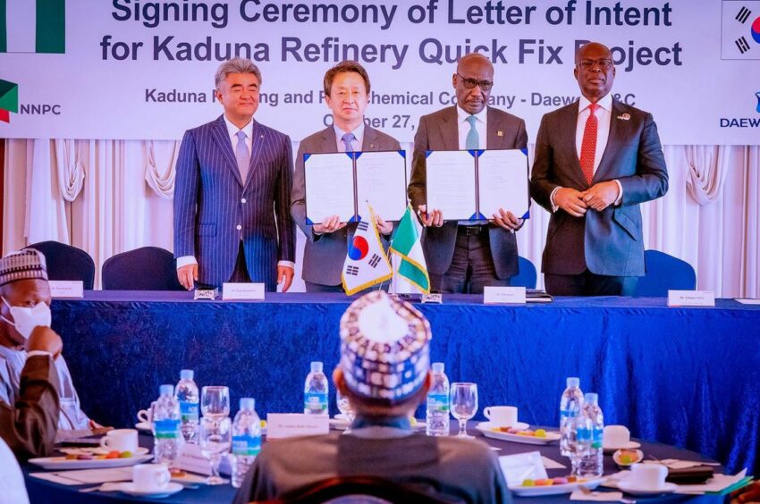 Four men stand behind table holding contract