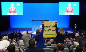 Demonstrators hold a banner as Prime Minister Liz Truss delivers her keynote speech at the Conservative Party annual conference at the International Convention Centre in Birmingham. Picture date: Wednesday October 5, 2022. PA Photo. See PA story POLITICS Tory. Photo credit should read: Jacob King/PA Wire