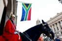 Soldier in red on horse with South African flag behind
