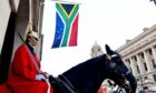 Soldier in red on horse with South African flag behind