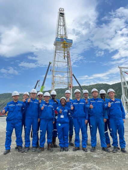 Group of workers in blue in front of a rig 