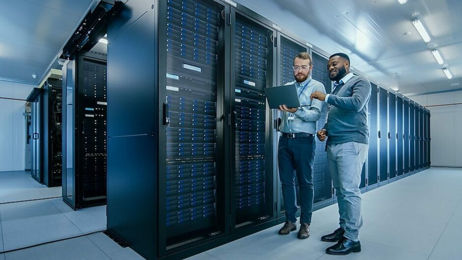 Two men look at a clipboard in data server room