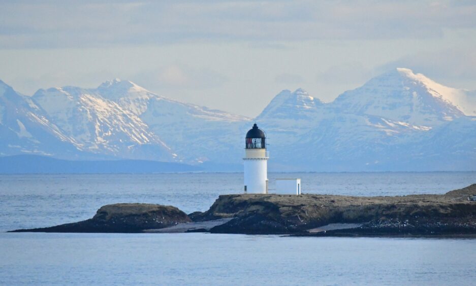 Arnish lighthouse at Stornoway with the snow-covered mainland hills in the background.