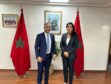 Two people stand between Moroccan flags