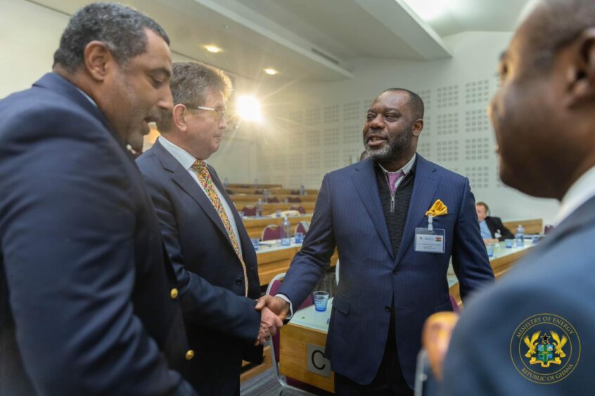 Men in suits shaking hands, light behind