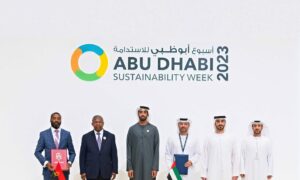 Men stand in front of white wall saying Abu Dhabi