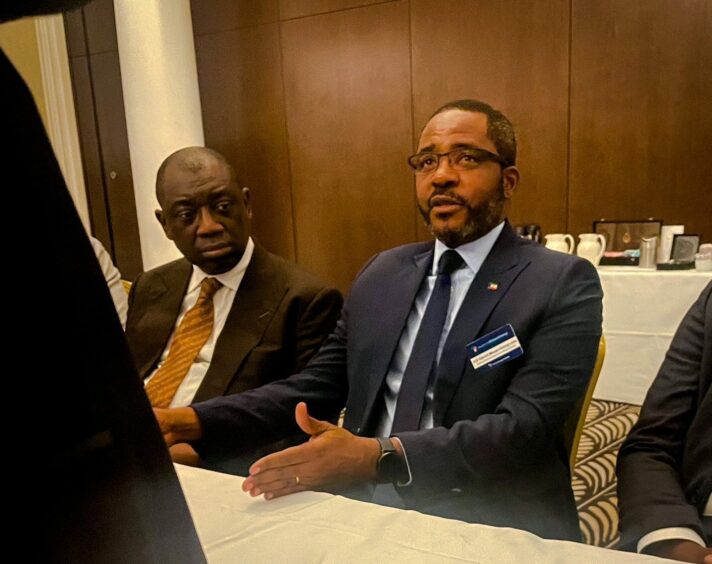 Men in suits sit at table gesturing