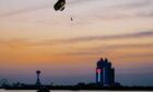 Sunset scene with parachute in air and giant flag on a building in background