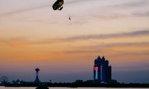 Sunset scene with parachute in air and giant flag on a building in background