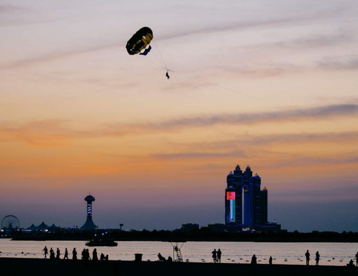 Sunset scene with parachute in air and giant flag on a building in background