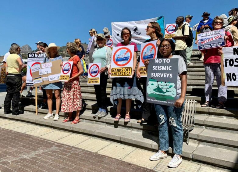 People hold placards standing on steps objecting to Russian seismic plans