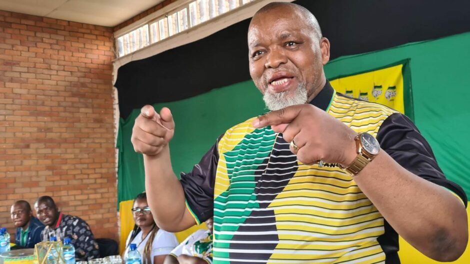 Man in stripey green black and yellow shirt waves hands