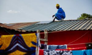 Installer on top of building, bright coloured prints in foreground