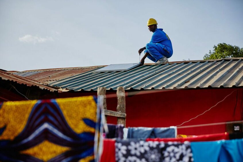 Installer on top of building, bright coloured prints in foreground