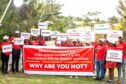 People in red hold up protests signs against EACOP