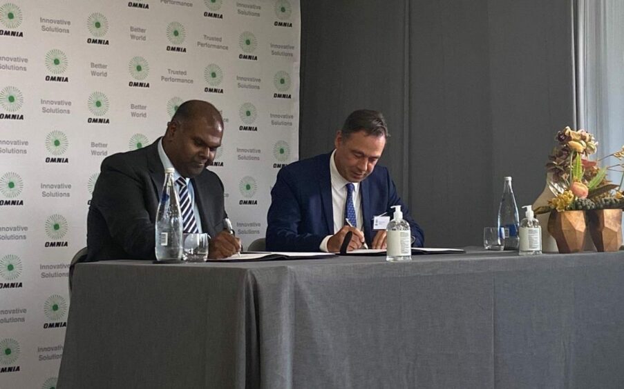 Two men sign documents at a table