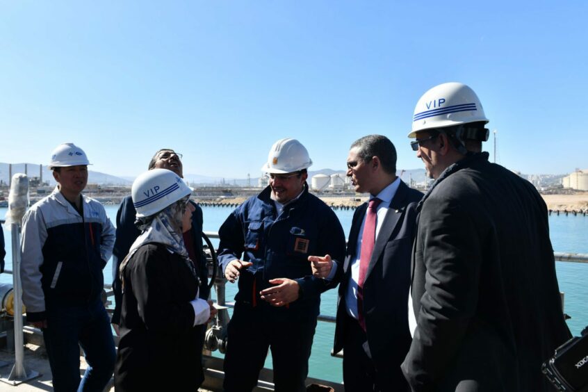 People in hard hats talk under a blue sky