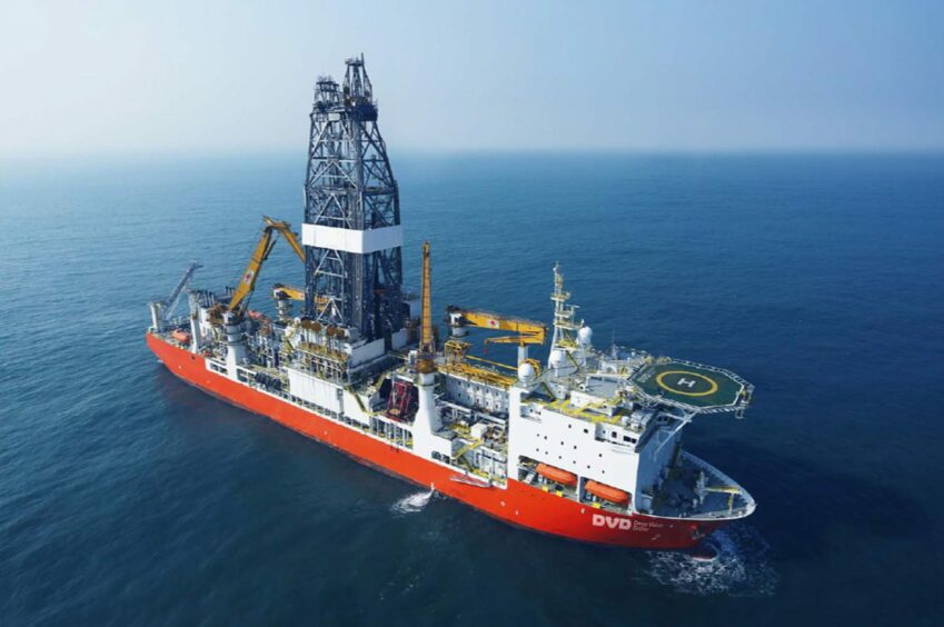 Drill ship with red hull in blue sea