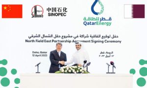 Two men shake hands in front of backdrop