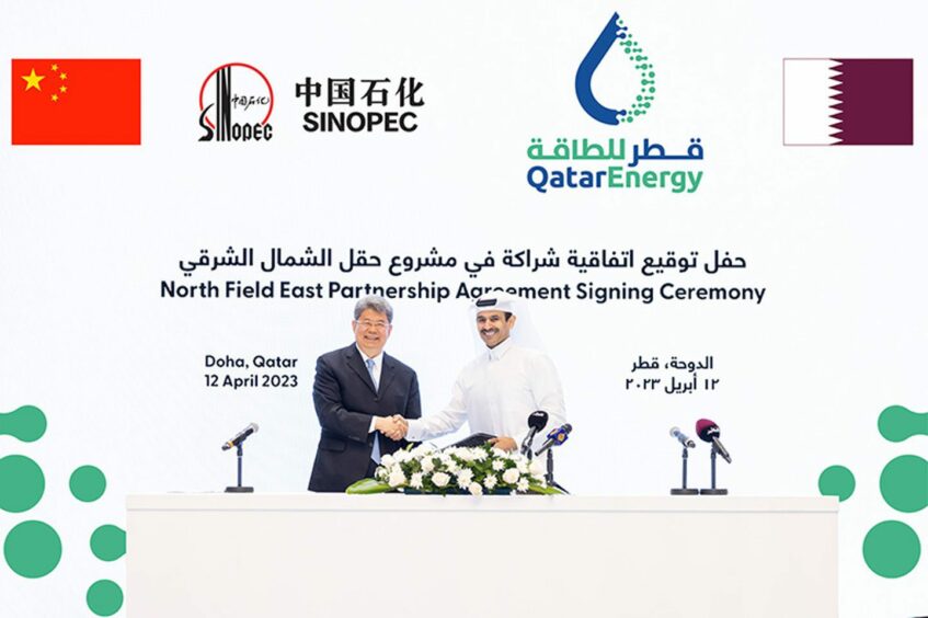 Two men shake hands in front of backdrop