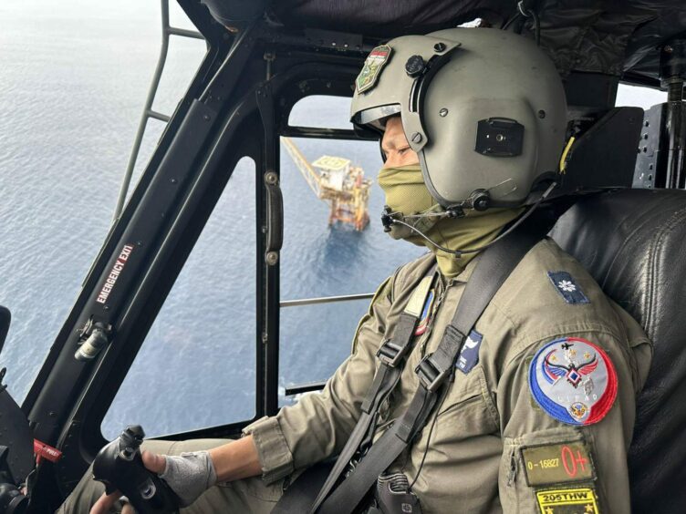 Helicopter pilot in foreground with platform through the window behind