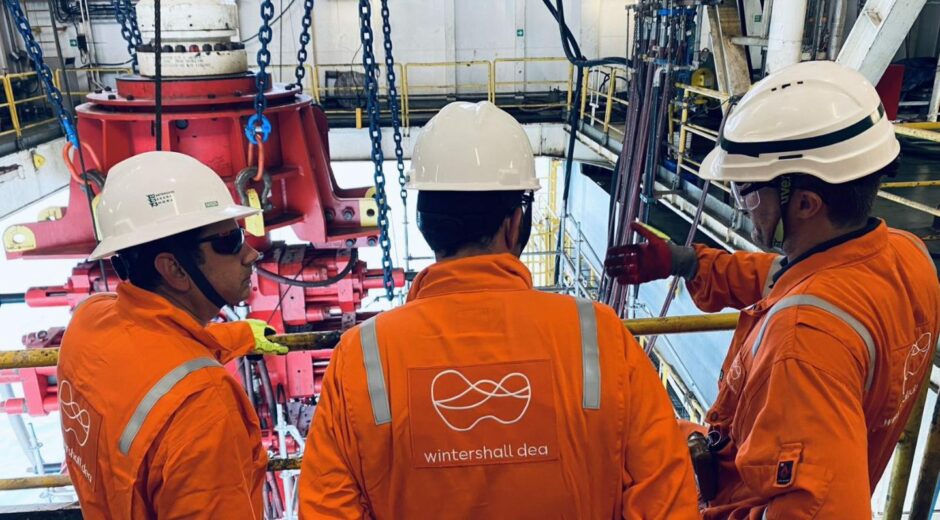 Three men in orange suits with Wintershall branding