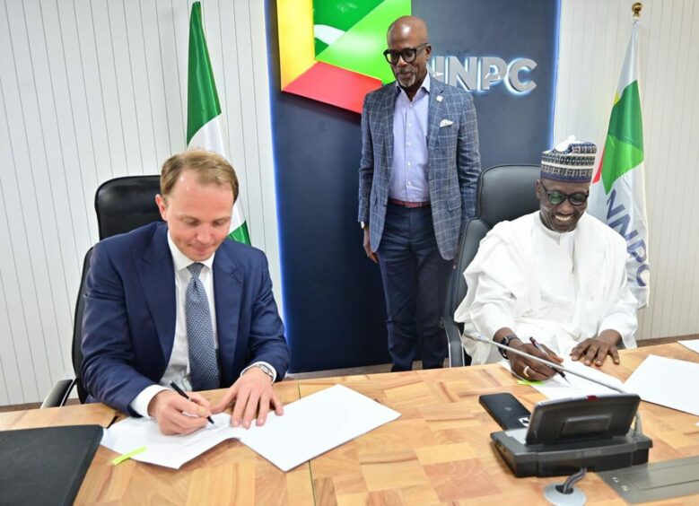 Two men seated sign documents