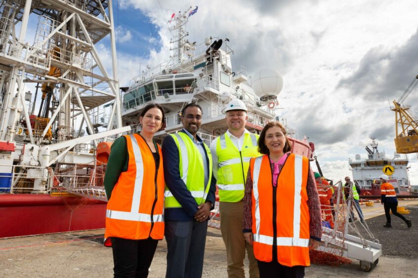 People in high vis vests stand in front of a ship