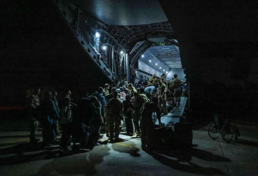 People climb onboard a plane in the dark