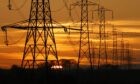 Sun setting behind a row of electricity pylons.