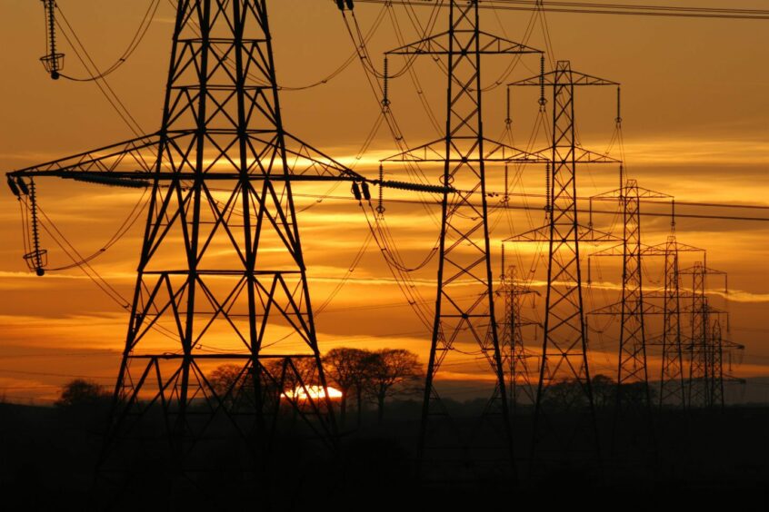 Sun setting behind a row of electricity pylons.
