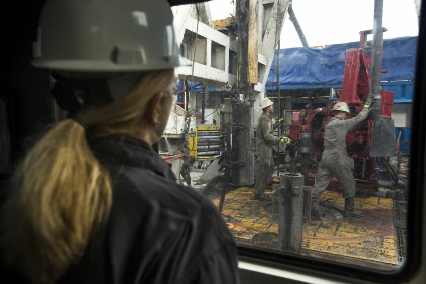 Rig hands thread together drilling pipe at a well site.