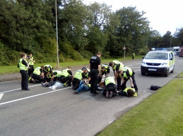 Six people from This is Rigged affixed themselves to Powdrake Road in Grangemouth with concrete and superglue.. Grangemouth.