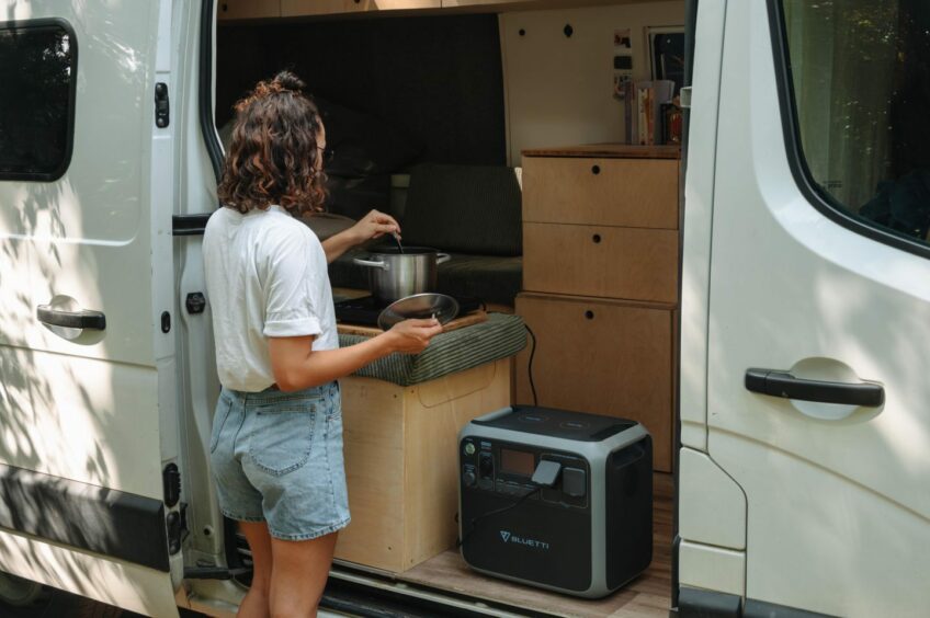 Woman using the BLUETTI AC200P to power a stove in her camper van.