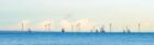 wide shot of wind turbines in the middle of the sea