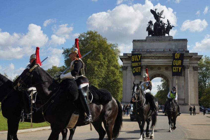 Fossil Free London draped two banners over Wellington Arch, near Buckingham Palace, during the Changing of the Guard procession demanding "oily money out of our city".