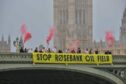 Fossil Free London Activists unveil a Stop Rosebank banner on Westminster Bridge in 2023.