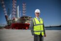 Bob Sanguinetti Chief Executive Officer at the completed south harbour with the Blue Tern multi-purpose, four-legged and self-propelled DP2 jack-up offshore wind turbine construction vessel in the back ground.