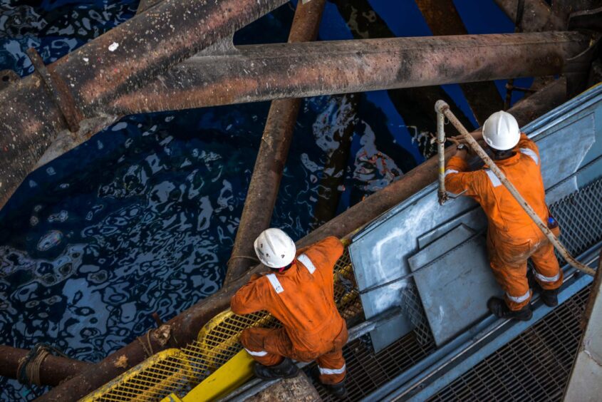 Two workers at jack up oil rig.
