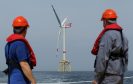 Workers look out at an offshore wind farm.