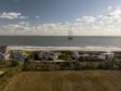 Beachfront homes near a lift boat, center, in Wainscott, New York, US, on Thursday, Dec. 1, 2022. The vessel's drill will be used in the construction of the South Fork Wind farm that will bore tunnels to bring electricity from the offshore wind farm that should start generating power in late 2023.