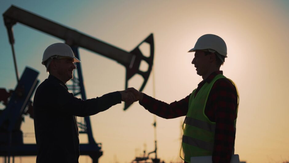 Two business people making a deal with oil pump in background