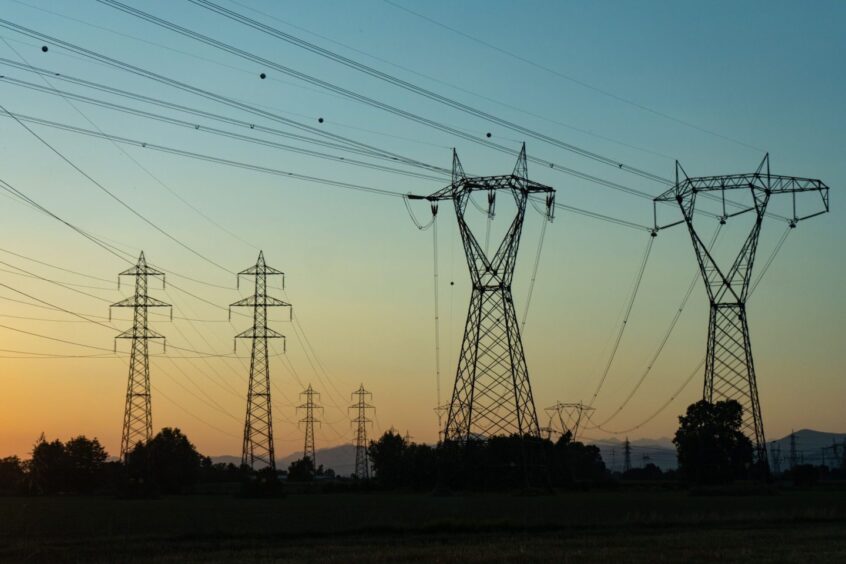 Electricity transmission towers and power lines against during sunset.