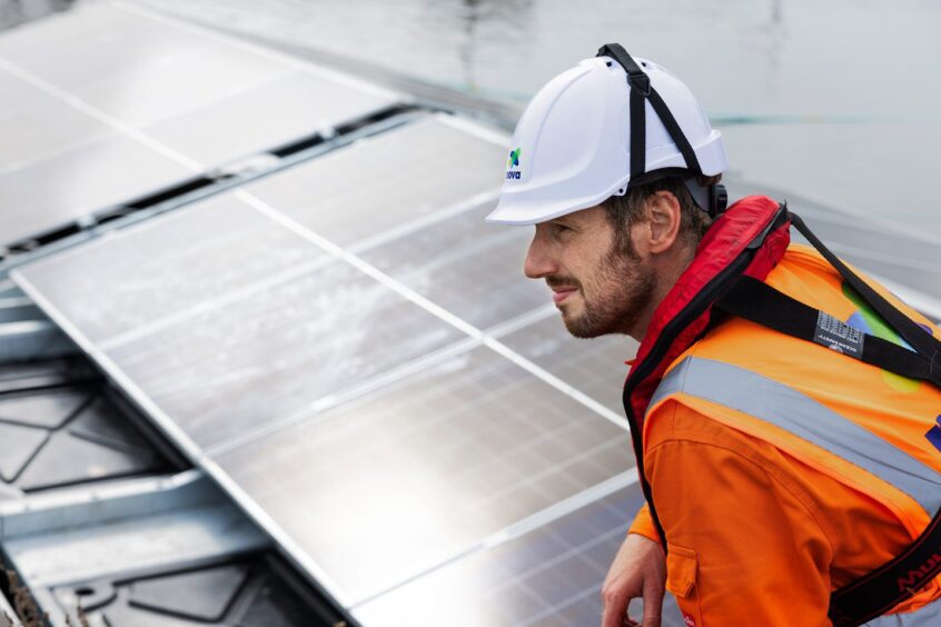 An AquaGen365 employee next to a floating solar panel installed at the Port of Leith.