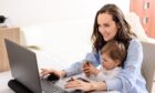 young smiling brunette mother in blue shirt working on laptop with her baby at home, working on maternity leave; Shutterstock ID 1709258893; Purchase Order: Keith Findlay; Job: Business desk editorial; 6d85a107-0557-414f-b7ef-d6b208b4527d