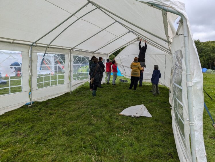 Activists stand on each other's shoulders to set up large tents.