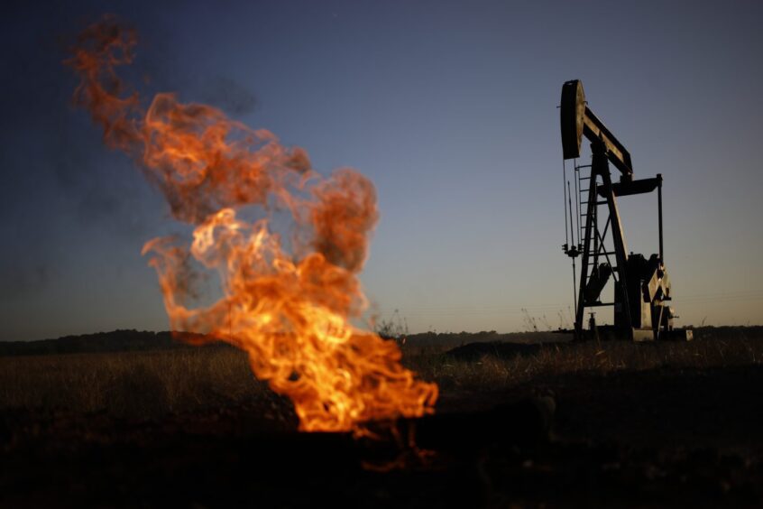 A natural gas flare burns near an oil pump jack at the New Harmony Oil Field in Grayville, Illinois, US, on Sunday, June 19, 2022. 