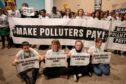 Protesters hold signs one saying Make Polluters Pay in the Caspian Plenary Hall in the Baku Olympic Stadium at COP29 UN Climate Conference. Image: Bianca Otero/ZUMA Press Wire/Shutterstock