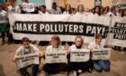 Protesters hold signs one saying Make Polluters Pay in the Caspian Plenary Hall in the Baku Olympic Stadium at COP29 UN Climate Conference. Image: Bianca Otero/ZUMA Press Wire/Shutterstock