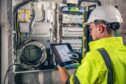 technician working on a switchboard with fuses, uses a tablet for an Ex inspection